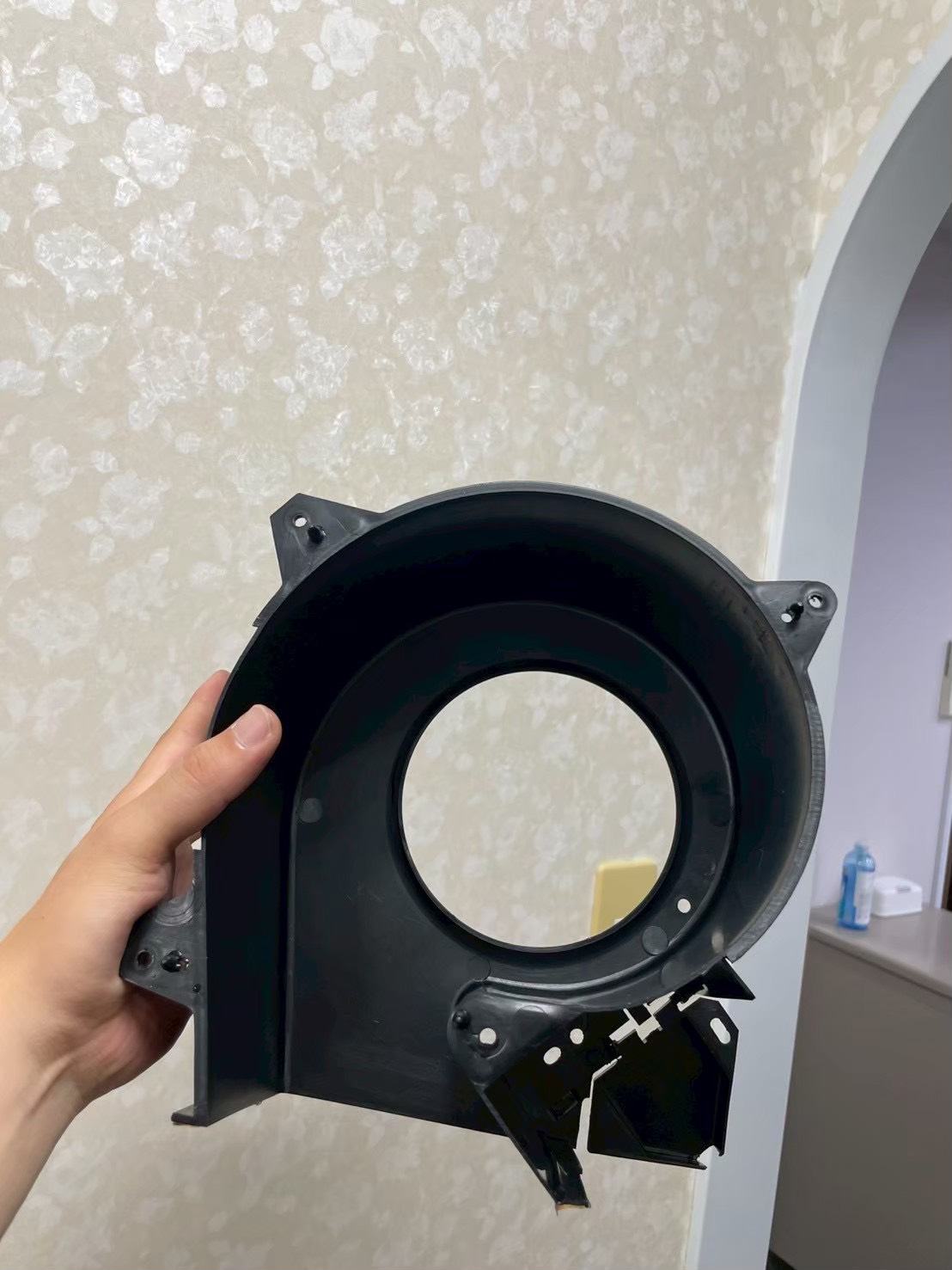 換気扇カバーを手に取り、分解した内部パーツを確認している様子